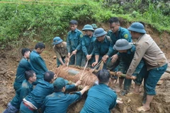 Chiến sỹ lực lượng vũ trang đưa bom xuống hố để hủy nổ. (Ảnh: TTXVN phát)