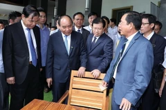 Thủ tướng Nguyễn Xuân Phúc và các đại biểu tham quan các sản phẩm đồ gỗ trưng bày tại hội nghị. (Ảnh: Thống Nhất/TTXVN)