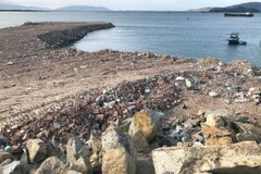 Hàng ngàn khối đất đá, xà bần đổ xuống lấp đầm Thị Nại. (Ảnh: Hà Linh/TTXVN)