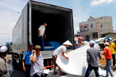 Nhân viên Công ty Kwong Lung - Meko di dời tài sản còn sót lại sau vụ cháy. (Ảnh: Thanh Liêm/TTXVN)