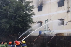 Lực lượng cứu hỏa phun nước dập tắt đám cháy trong nhà xưởng. (Ảnh: Thanh Liêm/TTXVN)