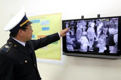 Cán bộ kiểm dịch Y tế cửa khẩu Hữu Nghị kiểm tra thân nhiệt của khách nhập cảnh qua màn hình của máy đo thân nhiệt. (Ảnh: Thái Thuần/TTXVN)