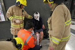 Lực lượng cứu hộ hỗ trợ người bị thương sau vụ phóng hỏa. (Nguồn: EPA/TTXVN)