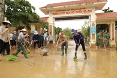 Lực lượng quân đội phối hợp cùng các giáo viên trường Tiểu học số 1 thị trấn Kiến Giang tổng vệ sinh môi trường sau khi lũ rút. (Ảnh: Vũ Sinh/TTXVN)