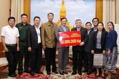 Đại sứ Nguyễn Bá Hùng trao cho Thứ trưởng Bộ Lao động và Phúc lợi xã hội Lào Padeumphone Xonthavy số tiền 50 triệu kip để giúp người dân Lào bị ảnh hưởng bởi lũ lụt nhanh chóng khắc phục và ổn định cuộc sống. (Ảnh: Phạm Kiên/Vietnam+)