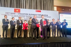 Đại diện Vietcombank, ông Phạm Quang Dũng, Tổng Giám đốc (hàng đầu, bên phải) và đại diện SBF, ông Ho Meng Kit – Giám đốc điều hành ký kết thỏa thuận hợp tác giữa hai bên. (Nguồn: Vietcombank)