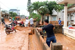 Đến trưa 2/10, người dân tại thôn Tiến Phú, xã Tiến Thành, thành phố Phan Thiết, vẫn khẩn trương dọn dẹp cát đỏ tràn vào nhà. (Ảnh: Nguyễn Thanh/TTXVN)