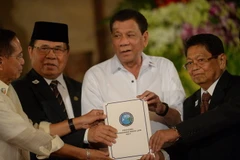 Tổng thống Rodrigo Duterte (giữa) và đại diện của MILF giơ cao dự luật mang tên “Luật Cơ bản Bangsamoro” tại buổi lễ ở Manila. (Nguồn: AFP/TTXVN)