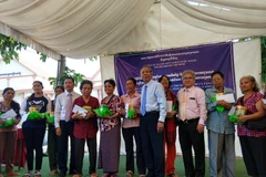 Ông Trần Đức Hiển, Phó Chủ nhiệm Ủy ban về người Việt Nam ở nước ngoài Thành phố Hồ Chí Minh cùng đại diện đoàn trao quà cho bà con. (Ảnh: Minh Hưng/TTXVN)
