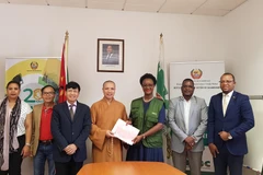 Thượng tọa Thích Đồng Huệ trao các văn bản liên quan đến lô hàng cứu trợ cho Tổng Giám đốc Cơ quan Quản lý thiên tai Mozambique Augusta Maíta. (Ảnh: Đình Lượng/TTXVN)