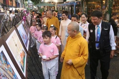 Đại biểu cùng các em nhỏ tham quan triển lãm. (Ảnh: Thu Hương/TTXVN)