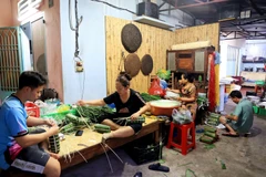 Con, cháu bà Ích cùng làm bánh tét. (Ảnh: Hồng Đạt/TTXVN)