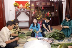 Bà Ma Thị Kim Cương cùng gia đình, bạn bè và con cháu đang cùng góp bánh chưng để ăn tết theo phong tục truyền thống của Việt Nam. (Ảnh: Bá Thành/TTXVN)