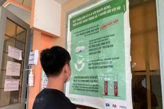 Một bạn trẻ đọc thông tin tuyên truyền về phòng chống HIV/AIDS và công tác điều trị. (Ảnh: T.G/Vietnam+)