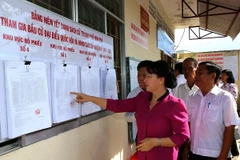 Chủ tịch Quốc hội Nguyễn Thị Kim Ngân kiểm tra nơi niêm yết danh sách cử tri tại khu phố Minh Phú, huyện Châu Thành. (Ảnh: Trọng Đức/TTXVN)