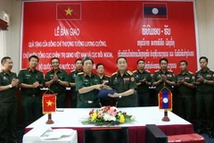 Đại tá Tào Văn Thái và Đại tá Inkong Viengdavong trao đổi biên bản giao, nhận thiết bị tại buổi lễ. (Ảnh: Phạm Kiên/TTXVN)