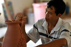 Người thợ gốm Phù Lãng tạo hoa văn cho sản phẩm. (Ảnh: Thanh Hà/TTXVN)