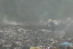 Rác vẫn âm ỉ cháy tại bãi rác xã Trường Thủy khiến khói bụi mù mịt. (Ảnh: Đức Thọ/TTXVN)