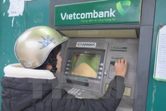 Khách hàng rút tiền tại ATM của Vietcombank. (Nguồn: TTXVN)