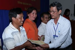 Đại diện Liên đoàn Lao động trao thẻ bảo hiểm cho các chủ tàu và ngư dân. (Ảnh: Anh Tuấn/TTXVN)