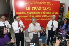 Bí thư Thành ủy Thành phố Hồ Chí Minh Nguyễn Văn Nên trao huy hiệu Đảng cho nhà thơ Lê Giang và nhạc sỹ Lư Nhất Vũ. (Ảnh: Chí Tưởng/TTXVN)