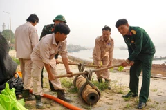 Các lực lượng chức năng tham gia xử lý quả bom. (Ảnh: TTXVN phát)