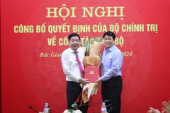 Ông Lương Cường (phải), Ủy viên Bộ Chính trị, Thường trực Ban Bí thư tặng hoa và trao quyết định cho đồng chí Nguyễn Văn Gấu nhận trọng trách mới. (Ảnh: Danh Lam/TTXVN)