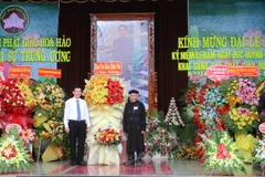 Phó Trưởng Ban Tôn giáo Chính phủ Nguyễn Ánh Chức (trái) tặng hoa, chúc mừng Đại lễ kỷ niệm 85 năm Ngày khai sáng đạo Phật giáo Hòa Hảo. (Ảnh: Công Mạo/TTXVN)