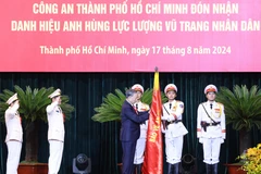 Tổng Bí thư, Chủ tịch nước Tô Lâm gắn Huy hiệu Anh hùng lực lượng vũ trang nhân dân lên lá cờ truyền thống của Công an Thành phố Hồ Chí Minh. (Ảnh: Lâm Khánh/TTXVN)