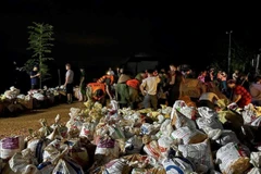 Hàng trăm người dân và các lực lượng chức năng vẫn đang khẩn trương chuyển các bao đất tới vị trí vỡ đê. (Ảnh: Quang Cường/TTXVN)