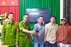 Công an phường 3 trả lại chiếc ví cho du khách ông Nguyễn Lê Trãi, 52 tuổi, trú tại huyện Diên Khánh, tỉnh Khánh Hòa trước sự chứng kiến của anh Thương và ông Khánh. (Ảnh: TTXVN phát)