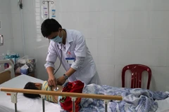 Cháu Nguyễn Giác Sáng được người nhà chăm sóc tại bệnh viện. (Ảnh: Ngọc Minh/TTXVN)