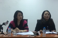 Bà Nguyễn Thị Thanh Hằng, Chánh văn phòng Ủy ban Nhân dân quận Long Biên (áo đỏ đen), thông tin về việc tạm dừng cải tạo nghĩa trang Bãi Xém. (Ảnh: Văn Thắng/Vietnam+)