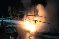Cảnh sát phòng cháy chữa cháy tỉnh Quảng Nam nỗ lực phun nước dập tắt đám cháy trên tàu câu mực. (Ảnh: Đoàn Hữu Trung/TTXVN)