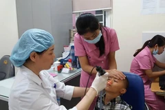 Bác sỹ khám cho trẻ có dị tật ở môi. (Ảnh: PV/Vietnam+)