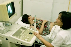 Nhân viên y tế kiểm tra sức khỏe sinh sản cho một phụ nữ. (Ảnh: TTXVN)