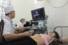 Bác sỹ đang thăm khám cho một bệnh nhân bảo hiểm y tế. (Ảnh: TTXVN)