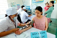 Nhân viên y tế khám sàng lọc tiêm chủng cho người dân. (Ảnh: TTXVN)