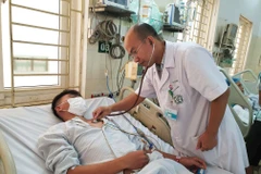 Tiến sỹ Lê Xuân Luật khám cho bệnh nhân điều trị sốt xuất huyết tại Trung tâm Nhiệt đới. (Ảnh: T.G/Vietnam+)