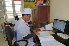 Nhân viên y tế kiểm tra sổ sách tại Trạm y tế xã Kim Chính, huyện Kim Sơn, Ninh Bình. (Ảnh: PV/Vietnam+)
