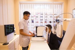 Chuyên viên khúc xạ kiểm tra thị lực cho khách hàng bằng máy đo khúc xạ. (Ảnh: PV/Vietnam+)