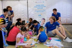 Các tình nguyện viên và các em nhỏ bị dị tật bẩm sinh. (Ảnh: PV/Vietnam+)