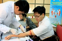 Cán bộ y tế lấy máu xét nghiệm cho người bệnh. (Ảnh: TTXVN/Vietnam+)