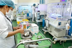 Nhân viên y tế thực hiện việc chăm sóc cho trẻ sơ sinh. (Ảnh: Dương Ngọc/TTXVN)