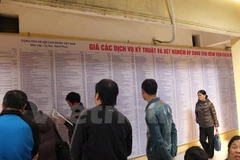 Người dân quan sát bảng giá viện phí mới tại một bệnh viện. (Ảnh: PV/Vietnam+)