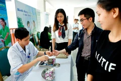 Nhân viên y tế xét nghiệm đường huyết cho người bệnh. (Ảnh: Dương Ngọc/TTXVN)