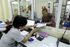 Người dân làm thủ tục khám chữa bệnh. (Ảnh: Dương Ngọc/TTXVN)