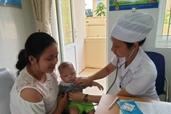 Nhân viên y tế chăm sóc sức khỏe cho trẻ nhỏ. (Ảnh: PV/Vietnam+)