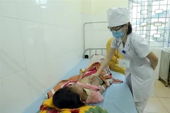 Bác sỹ chăm sóc cho bệnh nhân mắc sởi. (Ảnh: Tuấn Anh/TTXVN)