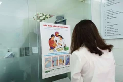 Người dân đọc thông tin tuyên truyền phòng chống bệnh viêm gan. (Ảnh: T.G/Vietnam+)